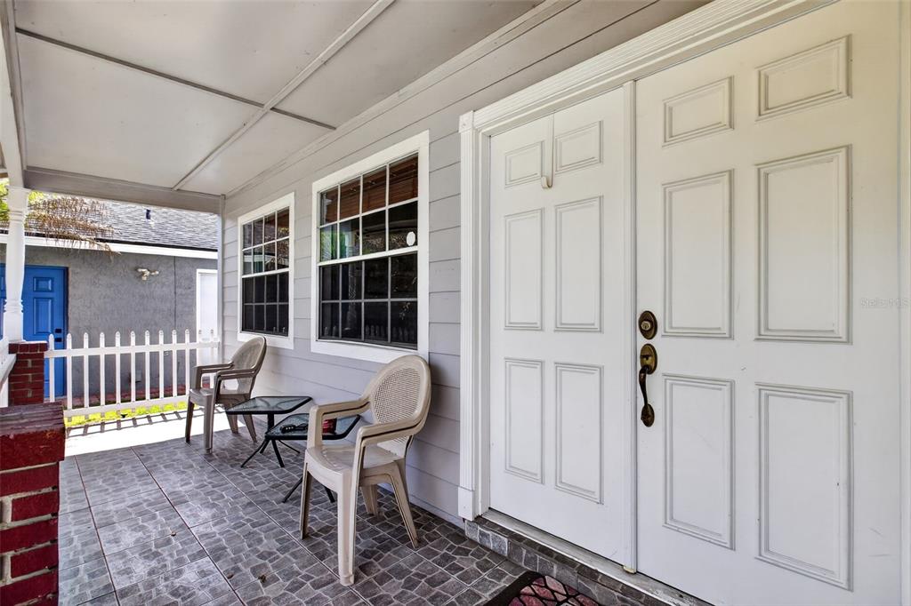 A covered porch features a tiled floor, two plastic chairs, and a white double door — 1564 LAWNDALE CIRCLE, WINTER PARK, FL