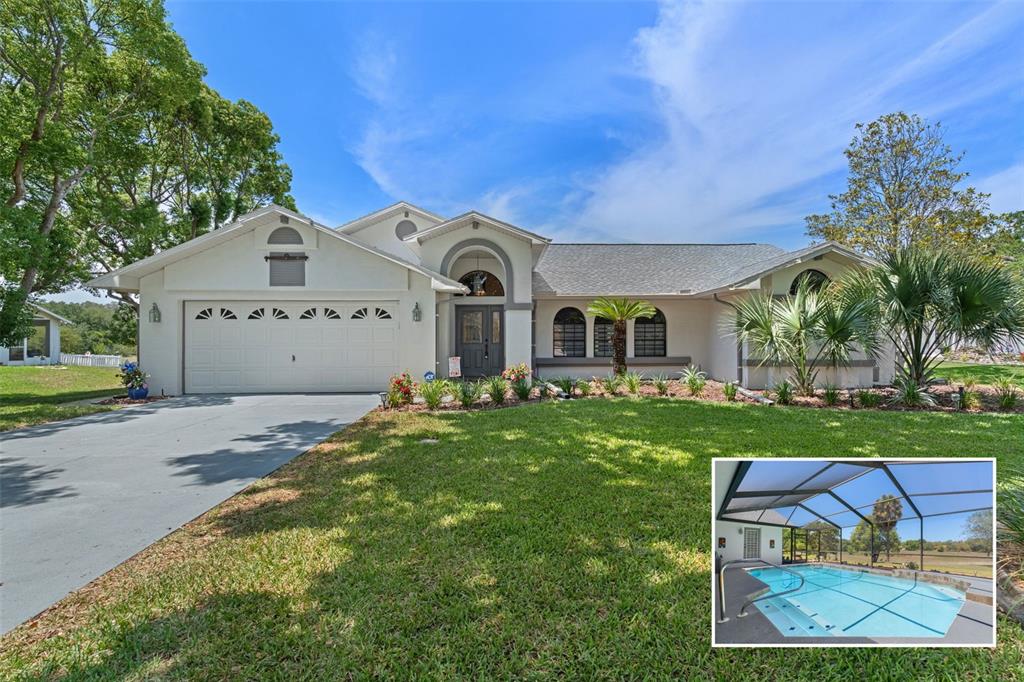 A single-story house with a two-car garage, arched entryway, and an inset pool photo — 18652 AUTUMN LAKE BOULEVARD, HUDSON, FL