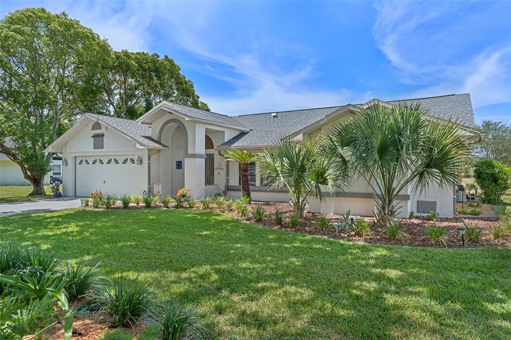 A single-story house with a two-car garage, light stucco exterior, and palm tree landscaping — 18652 AUTUMN LAKE BOULEVARD, HUDSON, FL