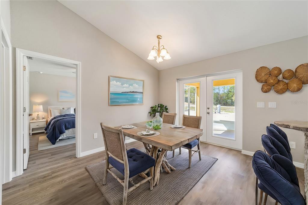 A dining area features a wooden table, blue chairs, and French doors leading outdoors — 12997 SW 88TH COURT, OCALA, FL