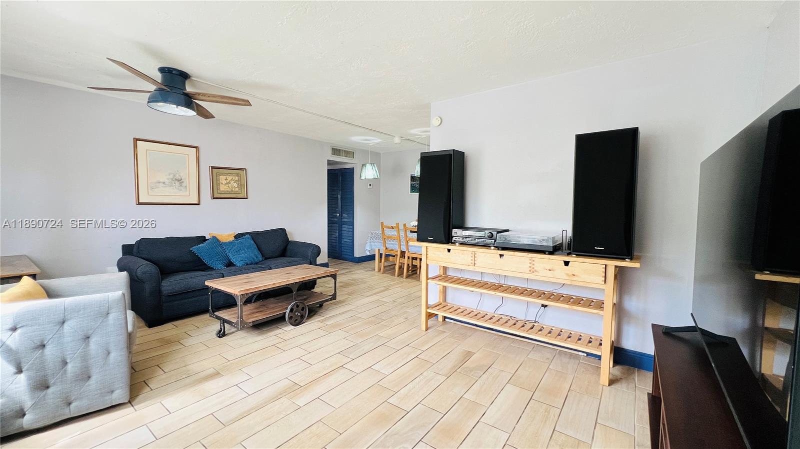A living room features light tile flooring, a dark sofa, and a wooden media console — 801 Meridian Ave # 1A, Miami Beach FL 33139, MIAMI BEACH, FL