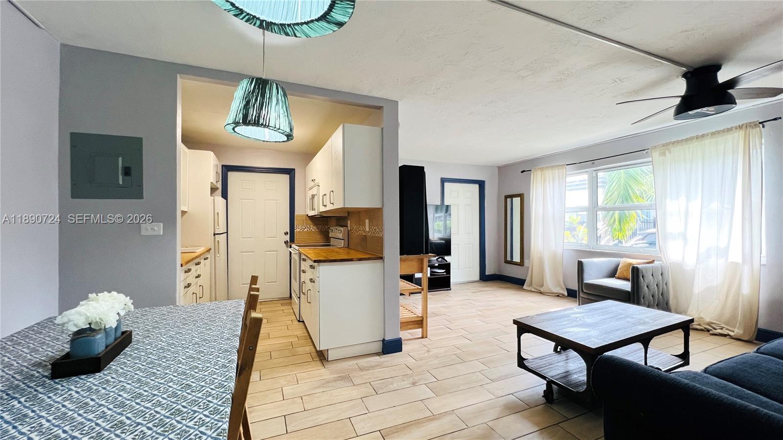 An open-concept living area features a kitchen with white cabinets and a dining space — 801 Meridian Ave # 1A, Miami Beach FL 33139, MIAMI BEACH, FL