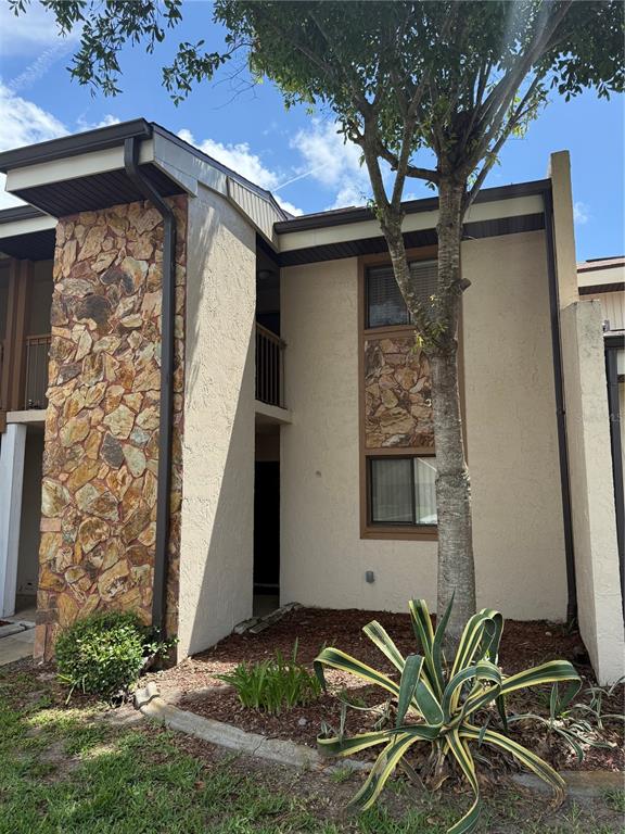 A two-story townhouse exterior features tan stucco walls, stone accents, and a small front garden — 7015 COGNAC DRIVE UNIT 6, NEW PORT RICHEY, FL