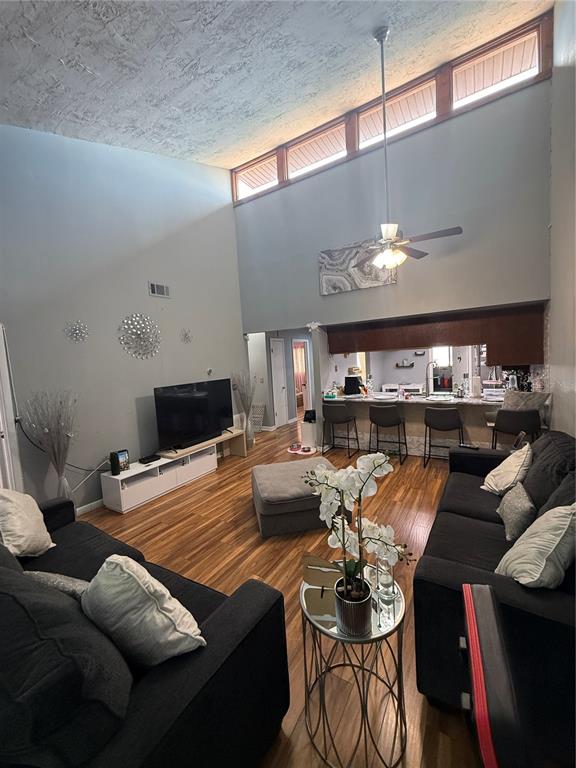 A living room with high ceilings, clerestory windows, wood flooring, and an open kitchen bar — 7015 COGNAC DRIVE UNIT 6, NEW PORT RICHEY, FL