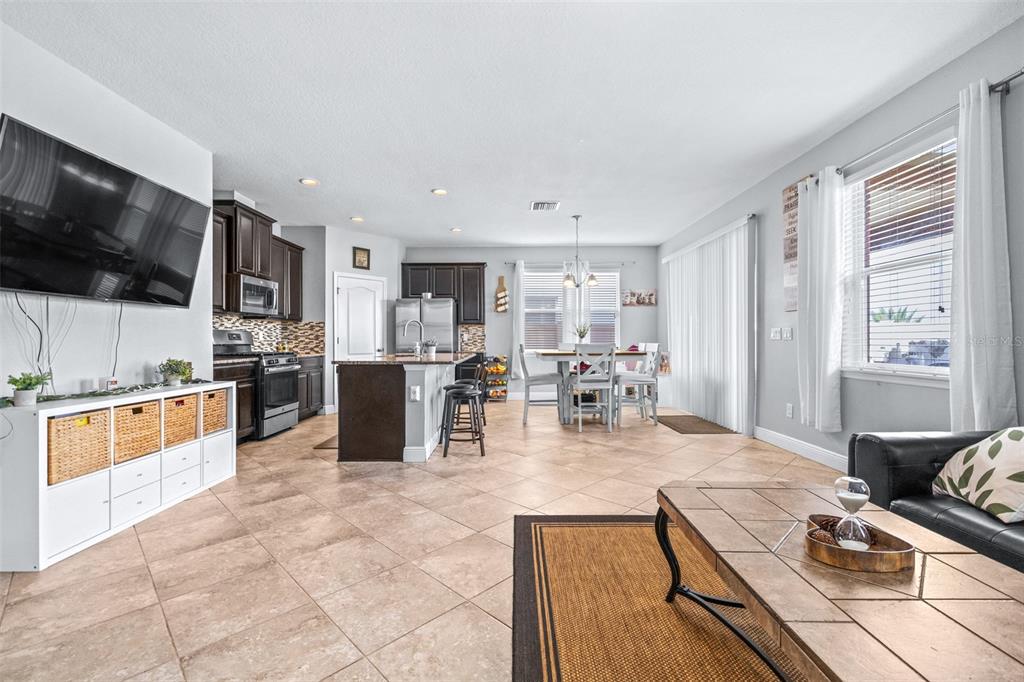 An open-concept living room and kitchen feature tile flooring, dark cabinetry, and a dining area — 11150 ABACO ISLAND AVENUE, RIVERVIEW, FL