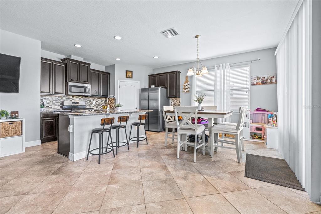 A kitchen with dark cabinets, granite countertops, and an island with bar stools — 11150 ABACO ISLAND AVENUE, RIVERVIEW, FL