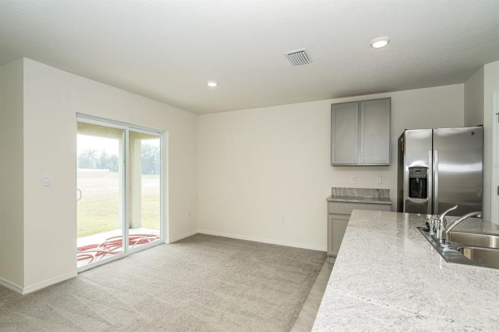 A kitchen and dining area with gray cabinets, granite countertops, and a sliding glass door — 796 SE 66TH TERRACE, OCALA, FL