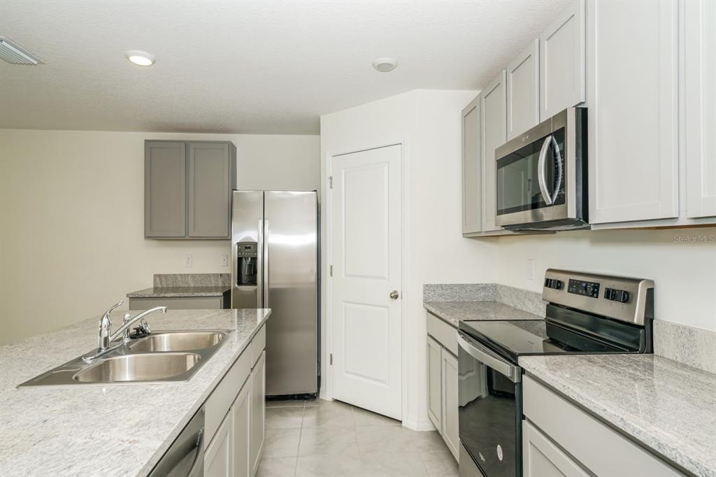 A kitchen with gray cabinets, granite countertops, stainless steel appliances, and a central island sink — 796 SE 66TH TERRACE, OCALA, FL