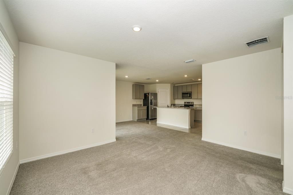 A carpeted living room opens into a kitchen with gray cabinets and a breakfast bar — 796 SE 66TH TERRACE, OCALA, FL