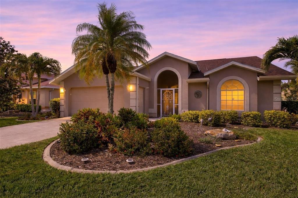 A single-story suburban house with a palm tree, a two-car garage, and a landscaped yard — 7015 PLEASANT HILL ROAD, BRADENTON, FL