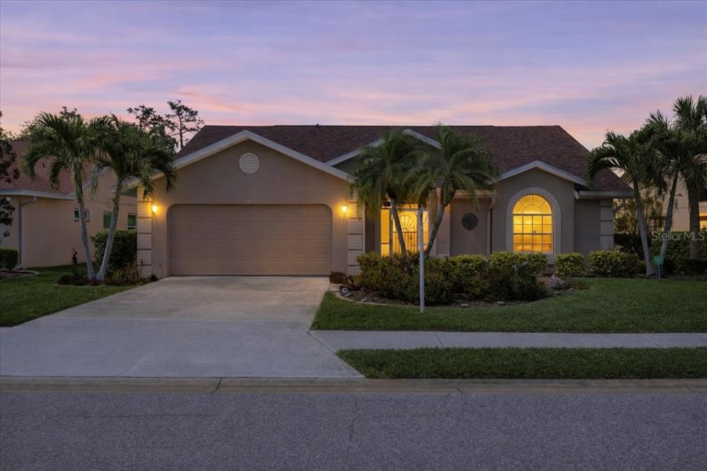 A single-story house with a two-car garage, palm trees, and a sunset sky — 7015 PLEASANT HILL ROAD, BRADENTON, FL