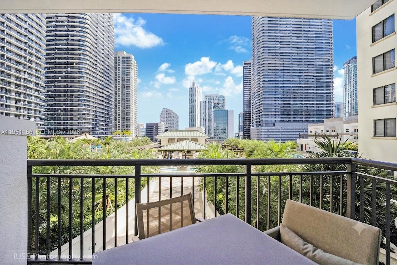 A balcony with a table and chairs overlooks a courtyard and surrounding high-rise buildings — 999 SW 1st Ave # 1208, Miami FL 33130, MIAMI, FL