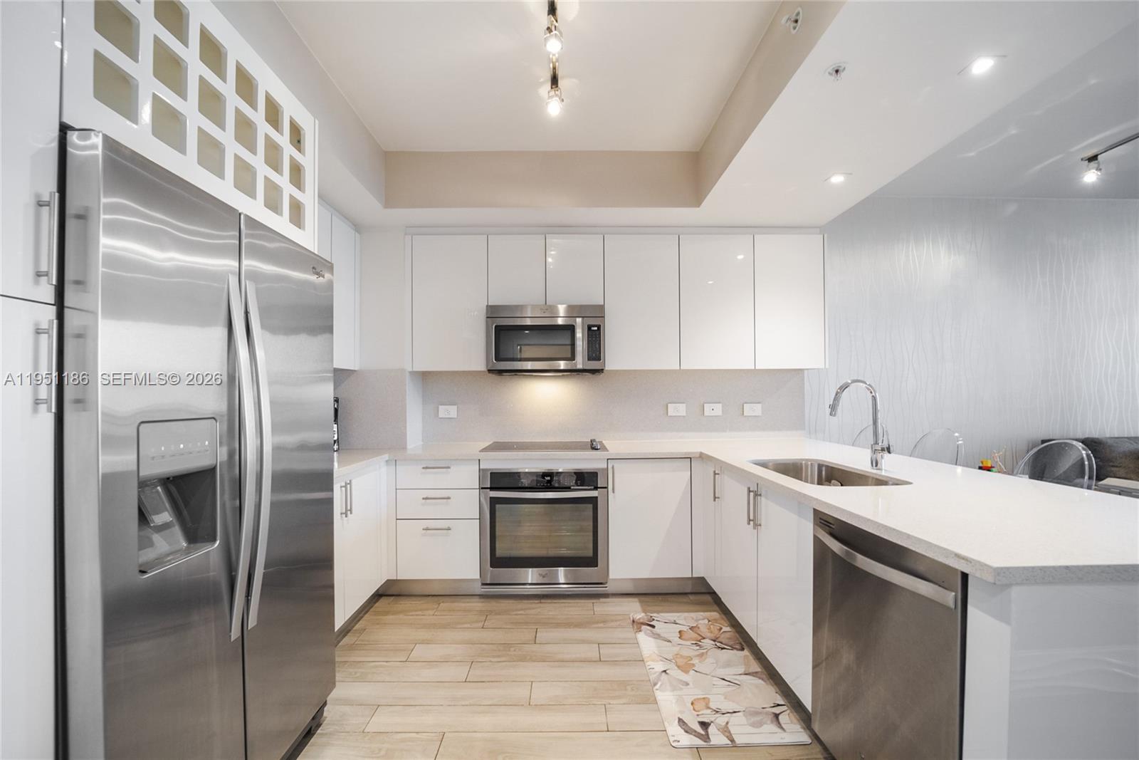A modern kitchen features white cabinets, stainless steel appliances, and light wood-look flooring — 999 SW 1st Ave # 1208, Miami FL 33130, MIAMI, FL