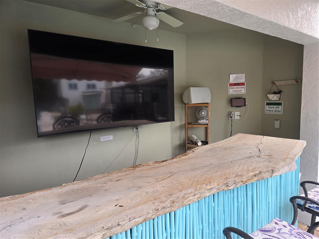An outdoor bar with a live-edge wood countertop and blue bamboo-style siding under a patio — 108 W 75TH STREET, BRADENTON, FL