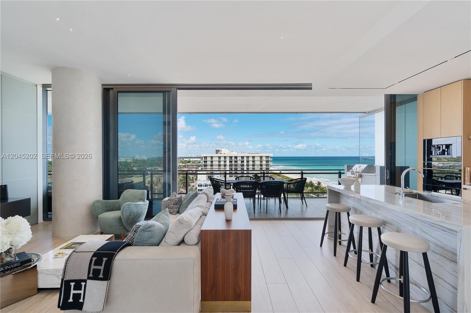 A modern living room and kitchen area open to a balcony with ocean views — 8701 Collins Ave # 1103, Miami Beach FL 33154, MIAMI BEACH, FL