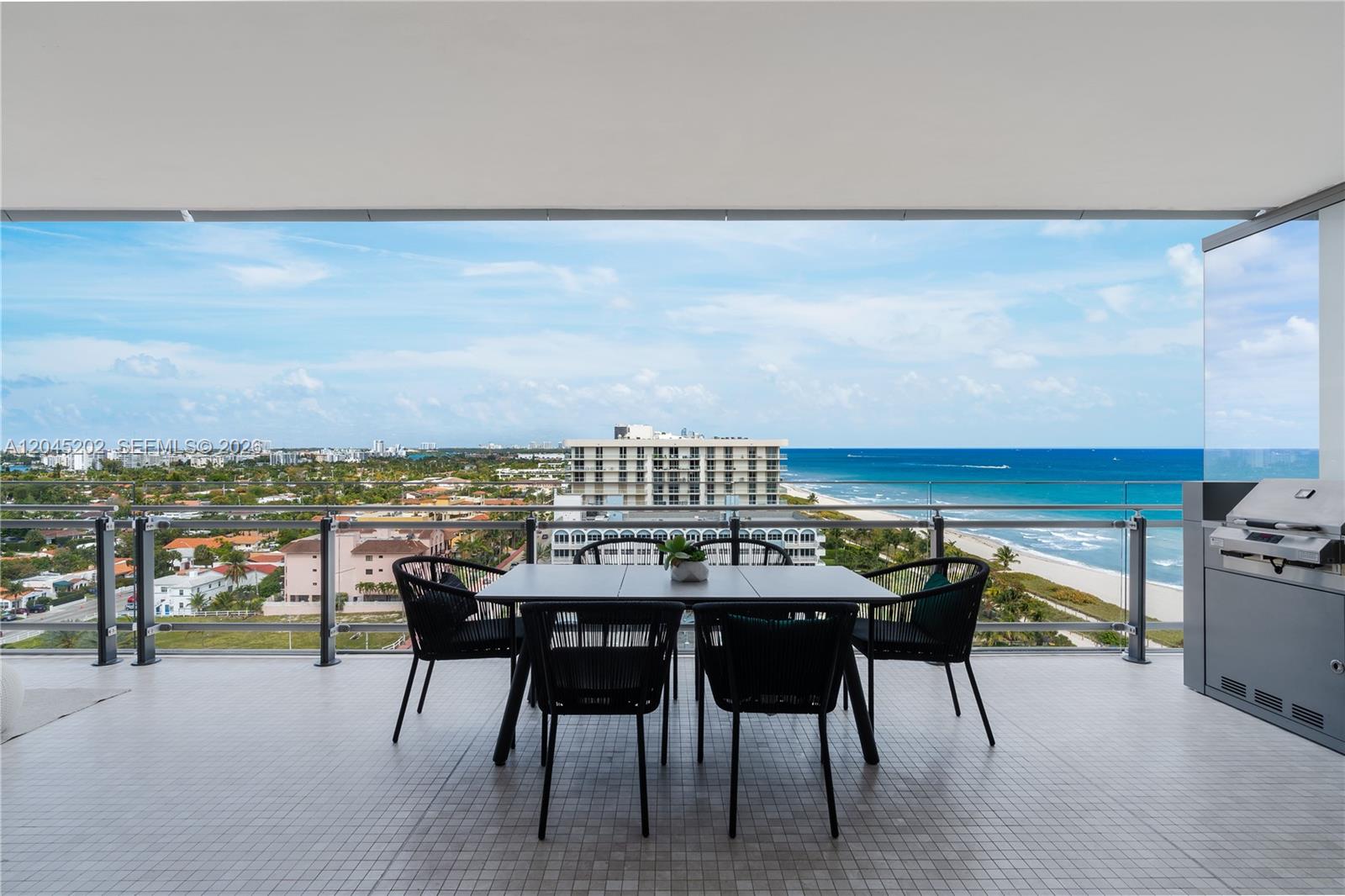 A balcony features a dining set and grill overlooking the ocean and city skyline — 8701 Collins Ave # 1103, Miami Beach FL 33154, MIAMI BEACH, FL
