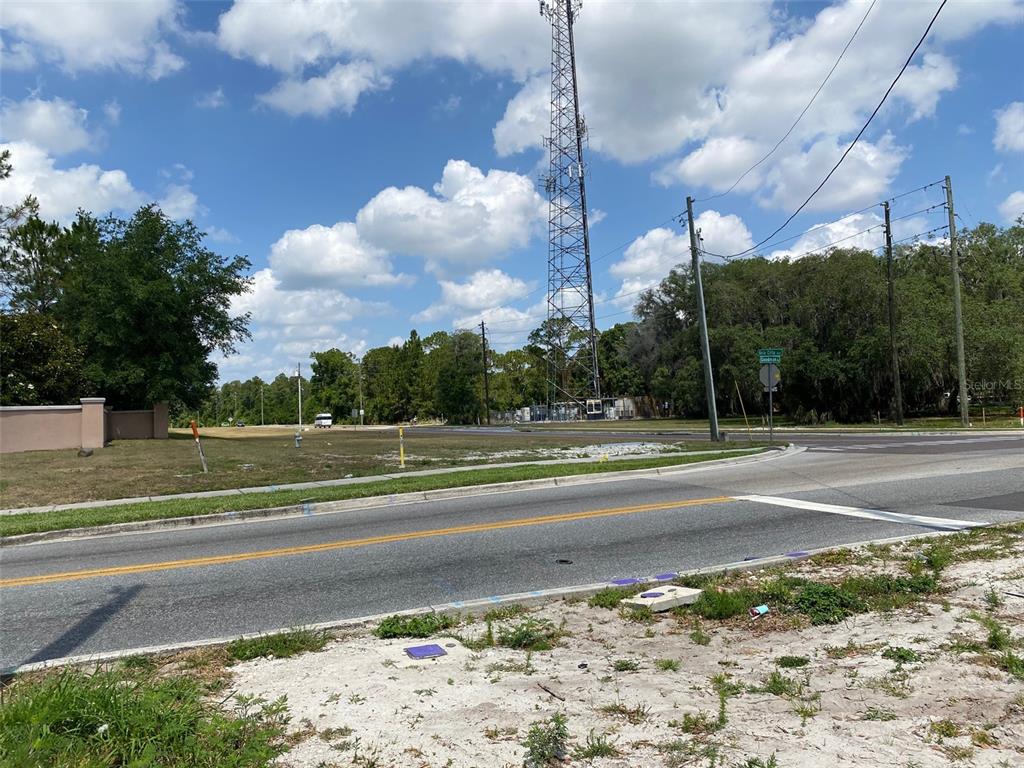 A vacant grassy lot features a tall communication tower and a street intersection — 8357 BELLA CITTA BOULEVARD, DAVENPORT, FL