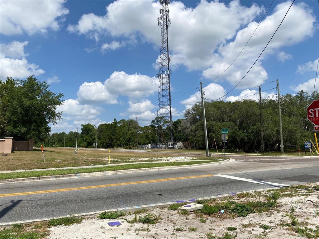 A tall communication tower stands near a road intersection with a stop sign and trees — 8357 BELLA CITTA BOULEVARD, DAVENPORT, FL