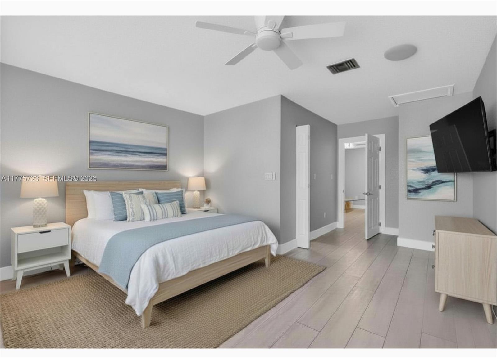 A bedroom features a light wood bed frame, gray walls, and a mounted television — 217 SE 5th St, Dania Beach FL 33004, DANIA BEACH, FL