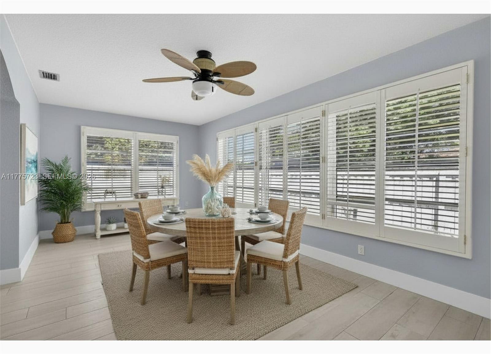 A dining room with a round table, wicker chairs, plantation shutters, and a ceiling fan — 217 SE 5th St, Dania Beach FL 33004, DANIA BEACH, FL