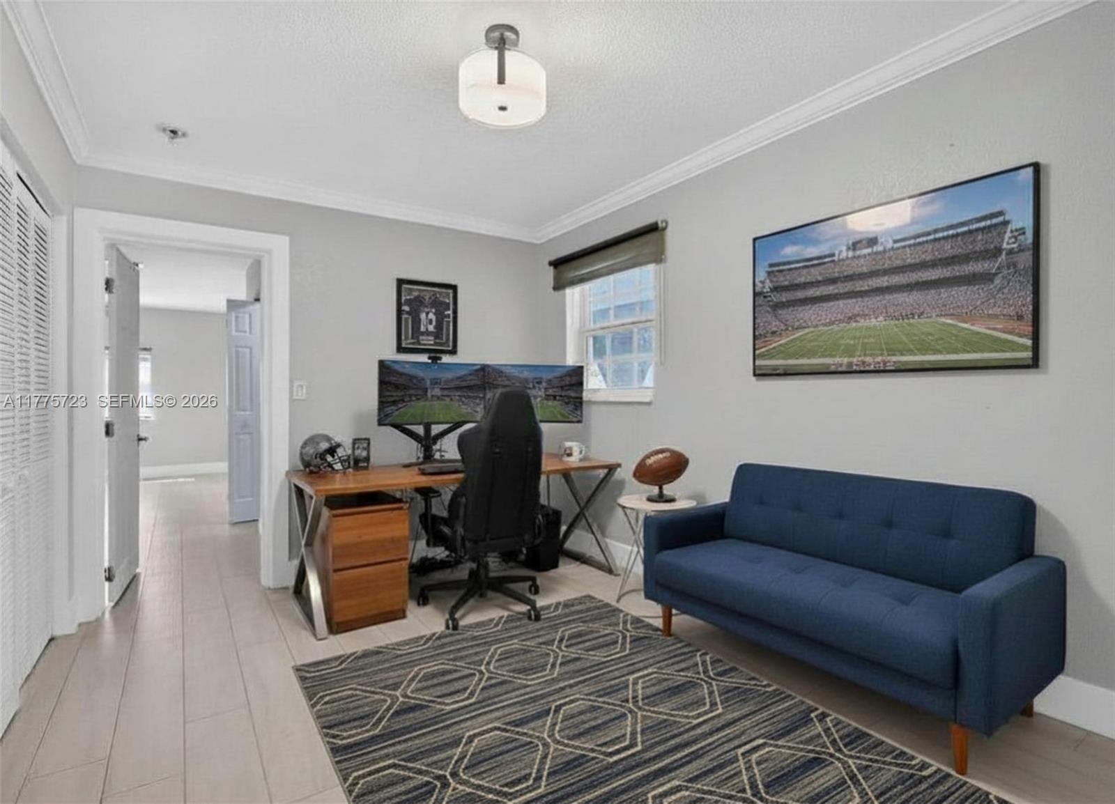 A home office features a desk with dual monitors, a blue sofa, and a patterned rug — 217 SE 5th St, Dania Beach FL 33004, DANIA BEACH, FL