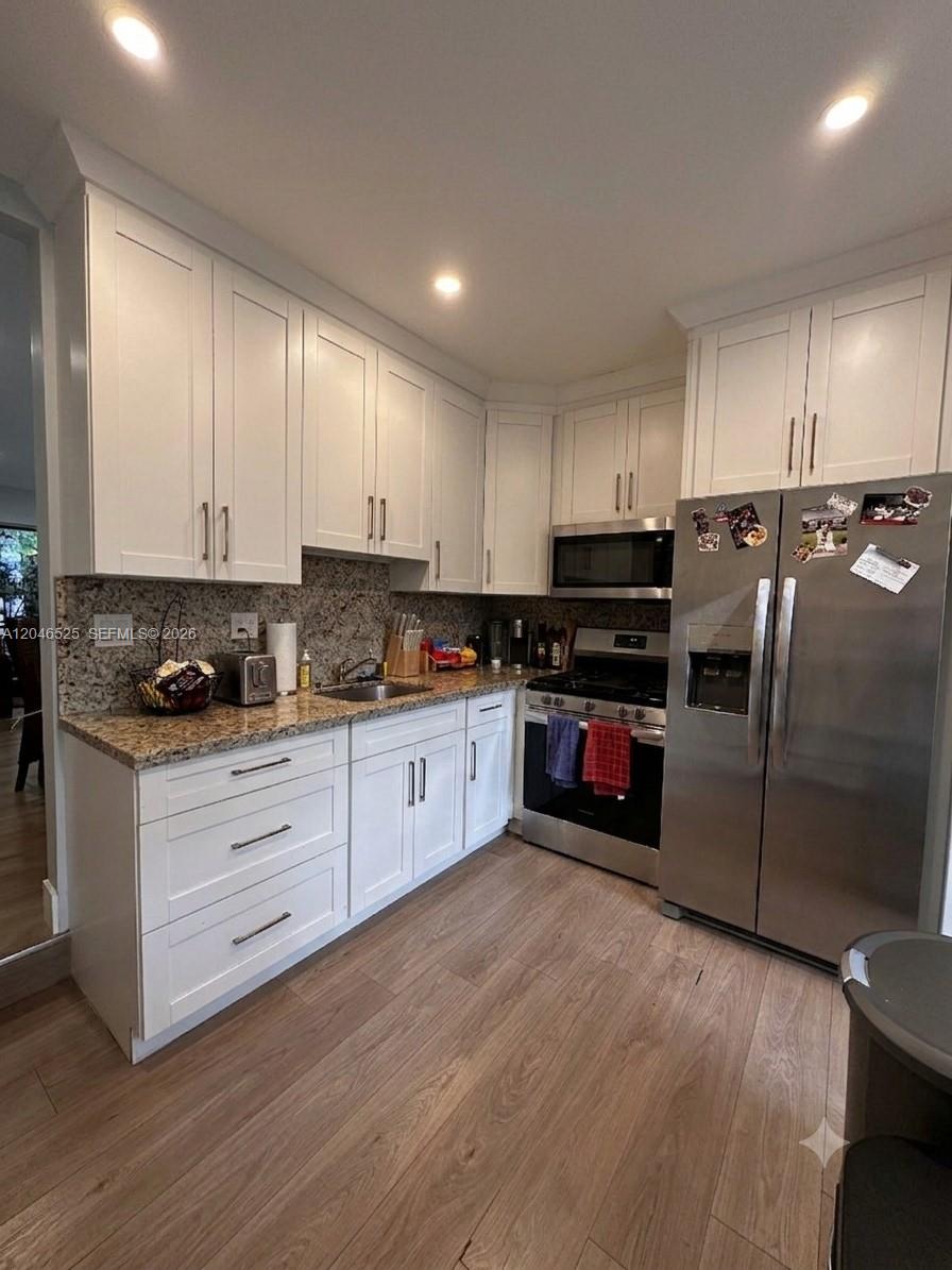 A kitchen features white cabinets, granite countertops, stainless steel appliances, and wood-look flooring — 3793 SW 28th St # 3793, Miami FL 33134, MIAMI, FL