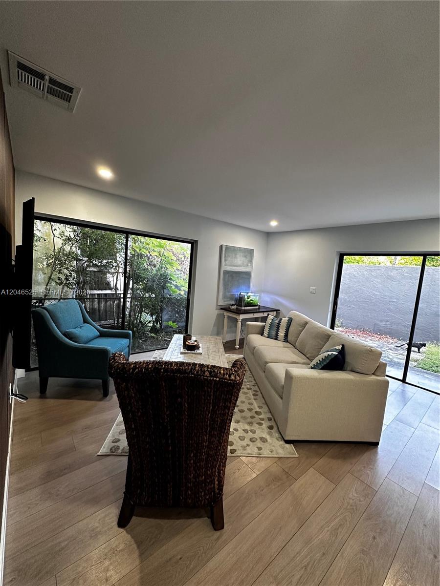 A living room features light wood flooring, a sofa, two chairs, and two sliding glass doors — 3793 SW 28th St # 3793, Miami FL 33134, MIAMI, FL