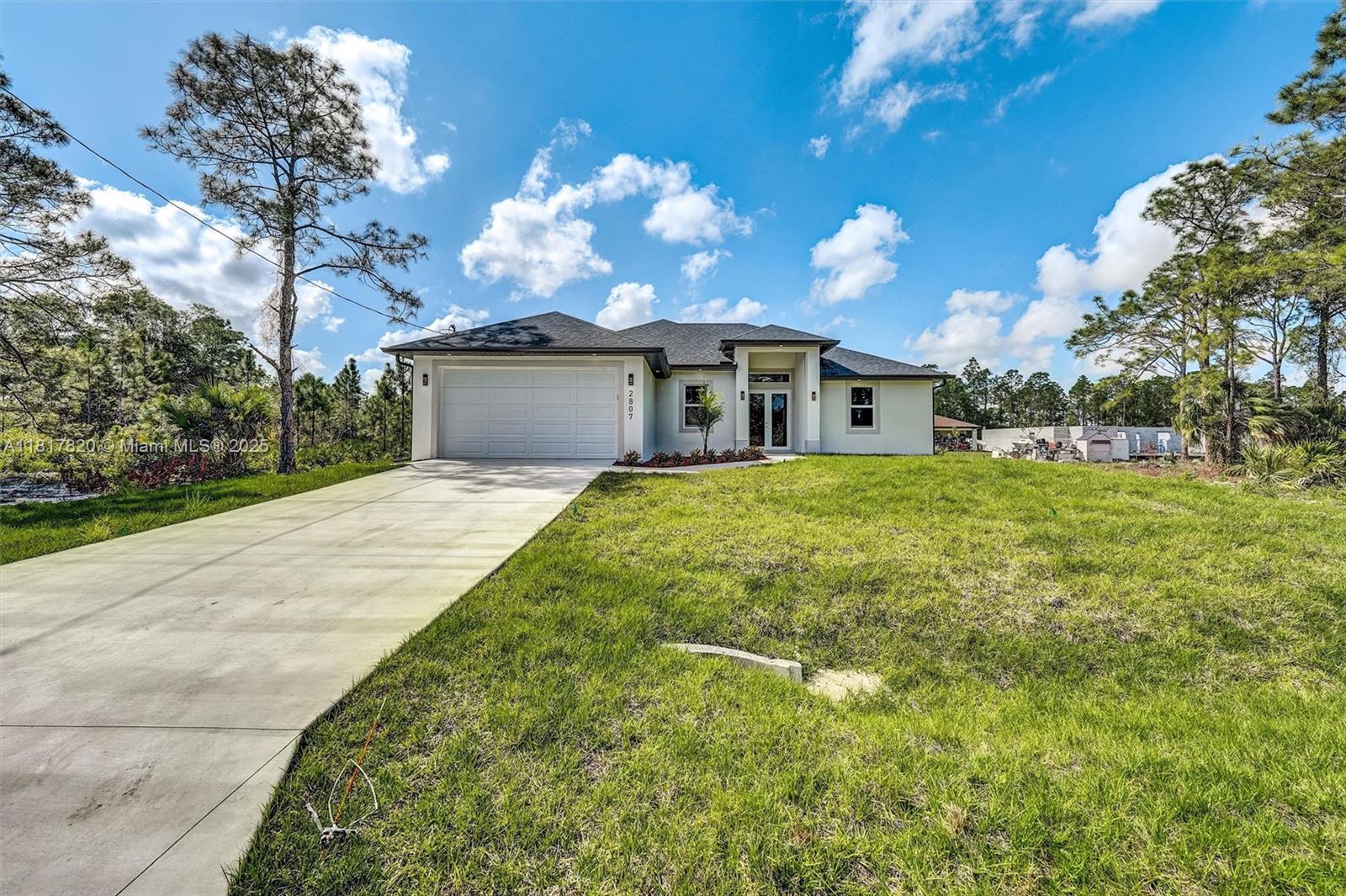A single-story house with a white exterior, a two-car garage, and a concrete driveway — 2807 40 ST W, Lehigh Acres FL 33971, LEHIGH ACRES, FL