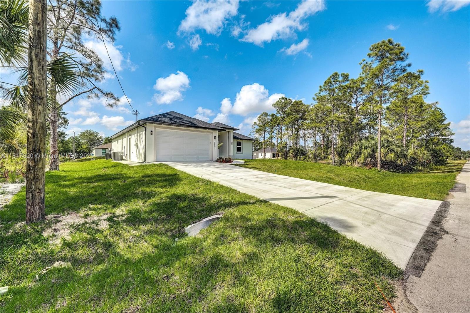 A single-story house with a white exterior, a two-car garage, and a concrete driveway — 2807 40 ST W, Lehigh Acres FL 33971, LEHIGH ACRES, FL