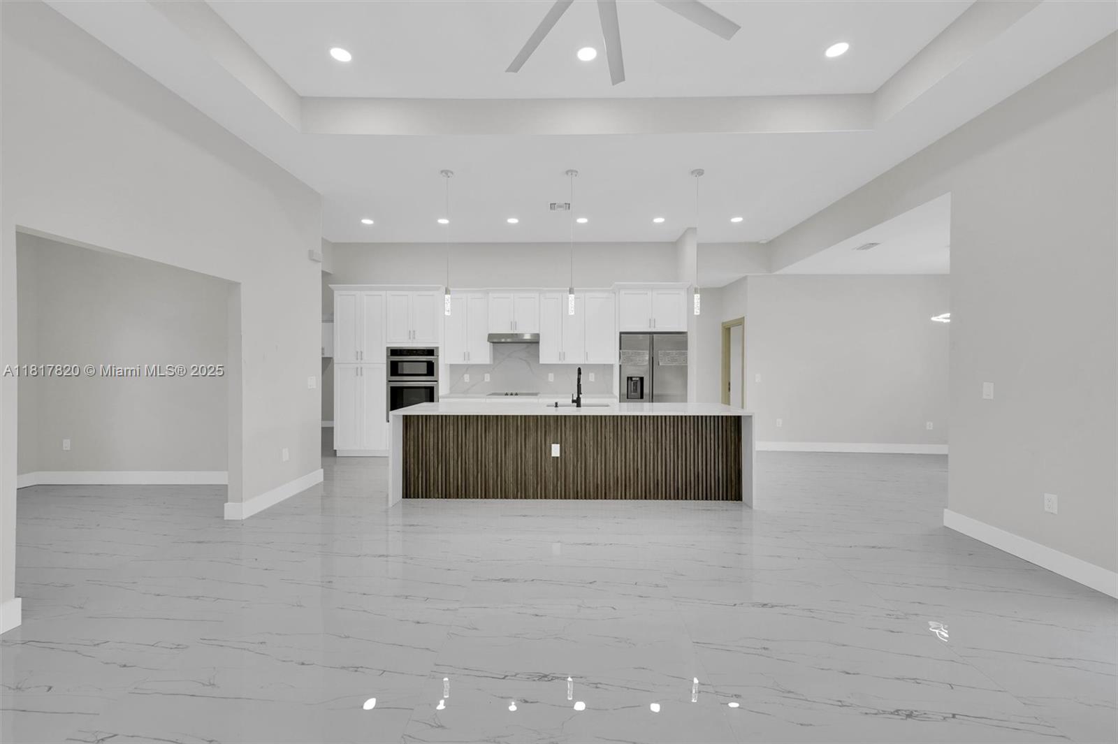 A modern kitchen features white cabinetry, a wood-slatted island, and light gray marble-look flooring — 2807 40 ST W, Lehigh Acres FL 33971, LEHIGH ACRES, FL