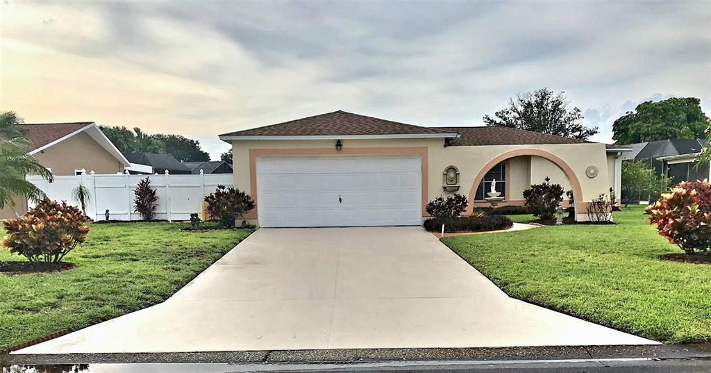 A single-story house with a white garage door, beige stucco exterior, and a concrete driveway — 6316 16TH AVENUE DRIVE W, BRADENTON, FL