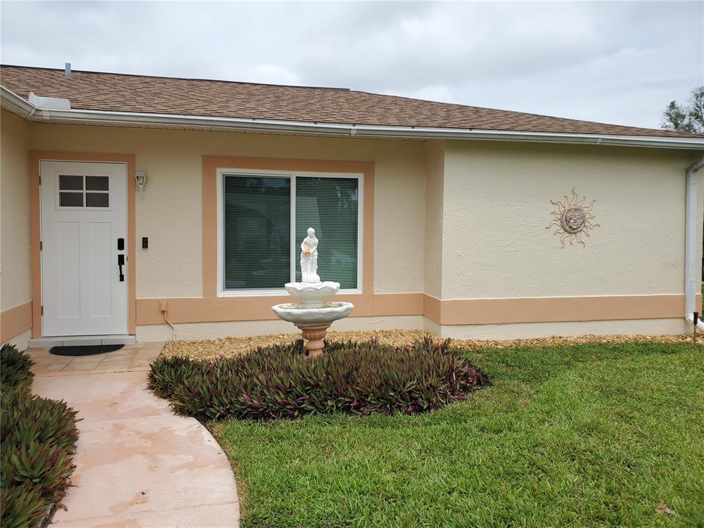 The exterior of a house features a white front door, a window, and a fountain — 6316 16TH AVENUE DRIVE W, BRADENTON, FL