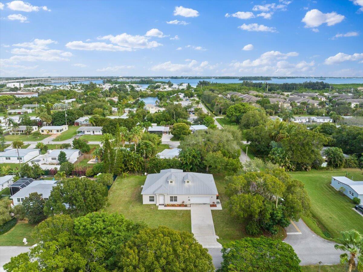 An aerial view shows a single-story house with a metal roof surrounded by green trees — 1410 4th Court, Vero Beach FL 32960, VERO BEACH, FL
