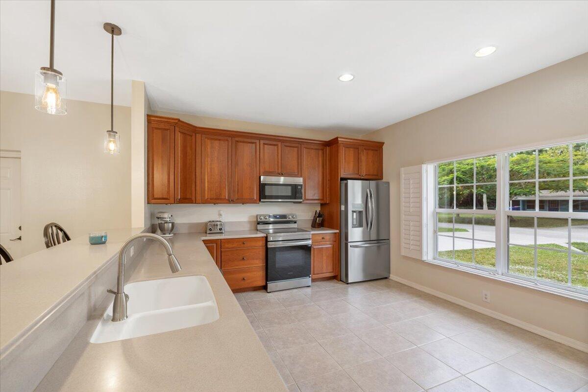 A kitchen features wood cabinets, stainless steel appliances, a sink, and a large window — 1410 4th Court, Vero Beach FL 32960, VERO BEACH, FL
