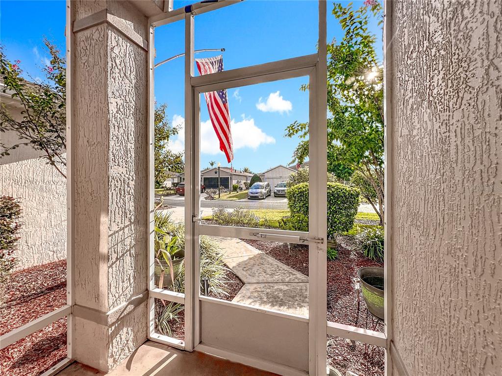 A view from a screened-in porch looking out toward a suburban street and houses — 1732 SW 157TH PLACE ROAD, OCALA, FL