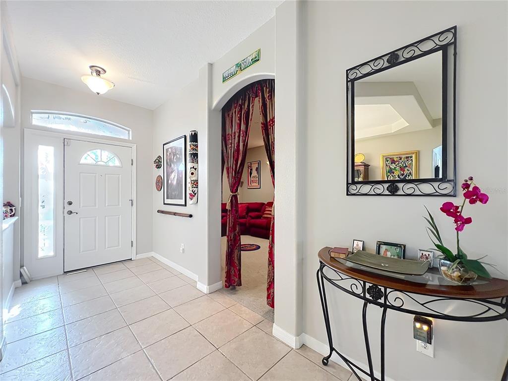 An entryway features tile flooring, a white front door, a console table, and an arched doorway — 1732 SW 157TH PLACE ROAD, OCALA, FL
