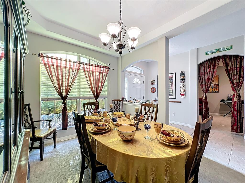 A dining room features a gold tablecloth, wooden chairs, a chandelier, and arched doorways — 1732 SW 157TH PLACE ROAD, OCALA, FL
