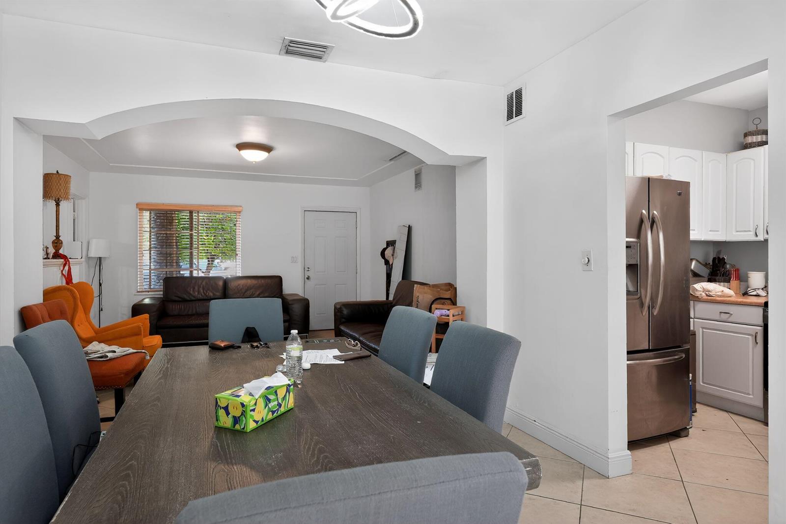 A dining area with a dark wood table sits adjacent to a living room and kitchen — 2131 Biarritz Drive, Miami Beach FL 33141, MIAMI BEACH, FL