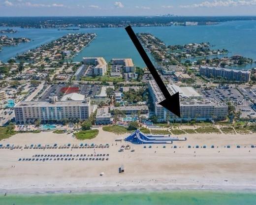 An aerial view shows beachfront condominium buildings with a large water slide on the sand — 5500 GULF BOULEVARD UNIT 3219, ST PETE BEACH, FL