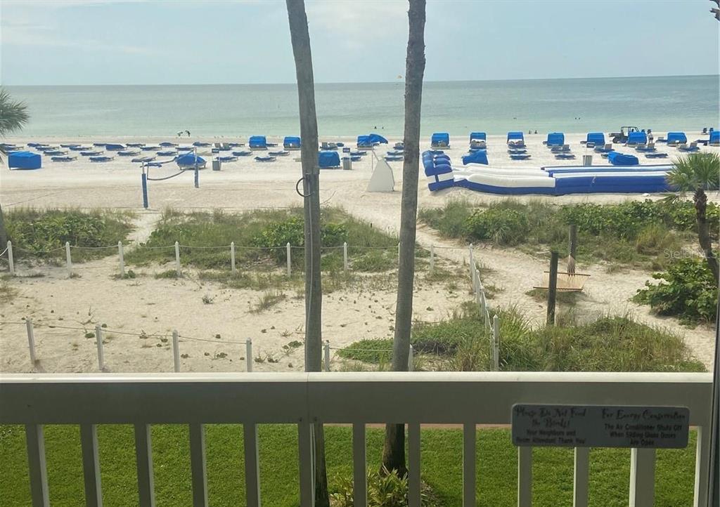 A balcony view overlooking a sandy beach with blue lounge chairs and the ocean — 5500 GULF BOULEVARD UNIT 3219, ST PETE BEACH, FL