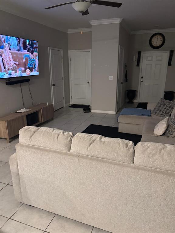 A living room features a large sectional sofa, a wall-mounted television, and tiled flooring — 11813 DUMAINE VALLEY ROAD, RIVERVIEW, FL