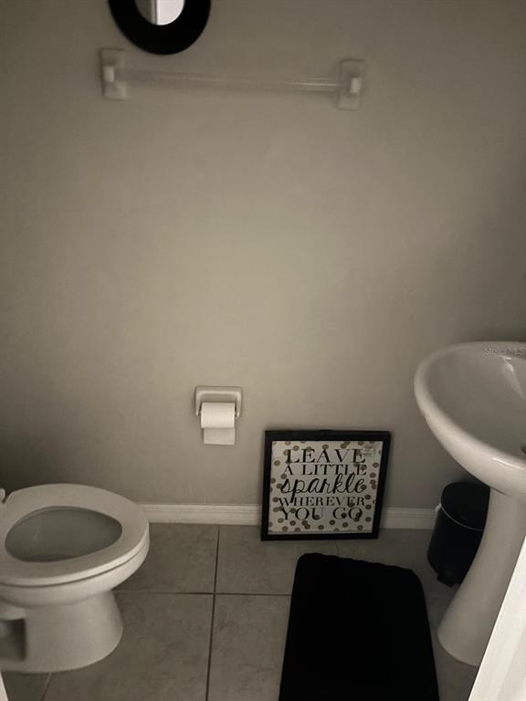 A small bathroom features a pedestal sink, a toilet, and a wall-mounted sign — 11813 DUMAINE VALLEY ROAD, RIVERVIEW, FL