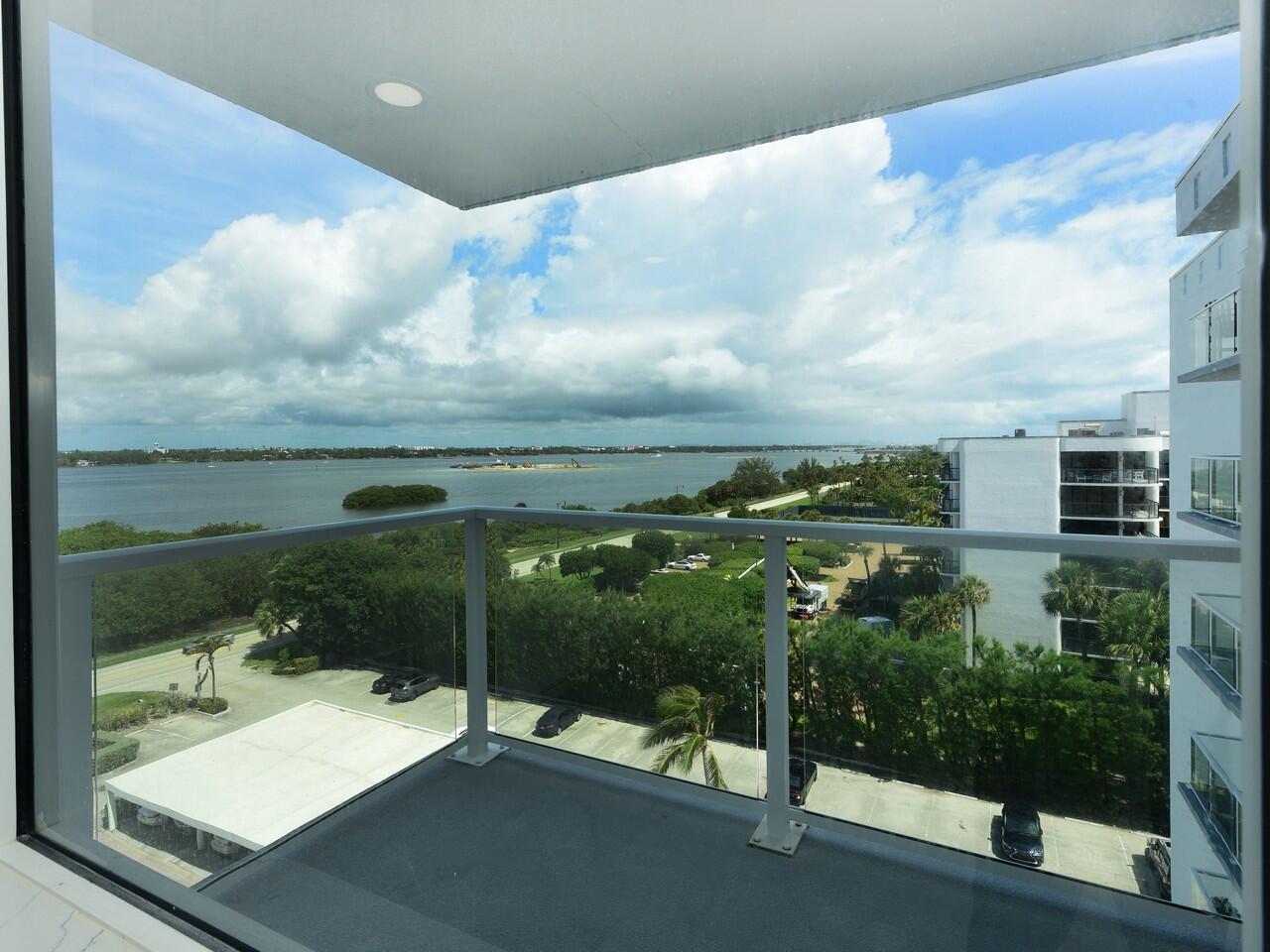 A view from a balcony overlooking a parking lot, green trees, and a large body of water — 3450 S Ocean Boulevard # 726, Palm Beach FL 33480, PALM BEACH, FL