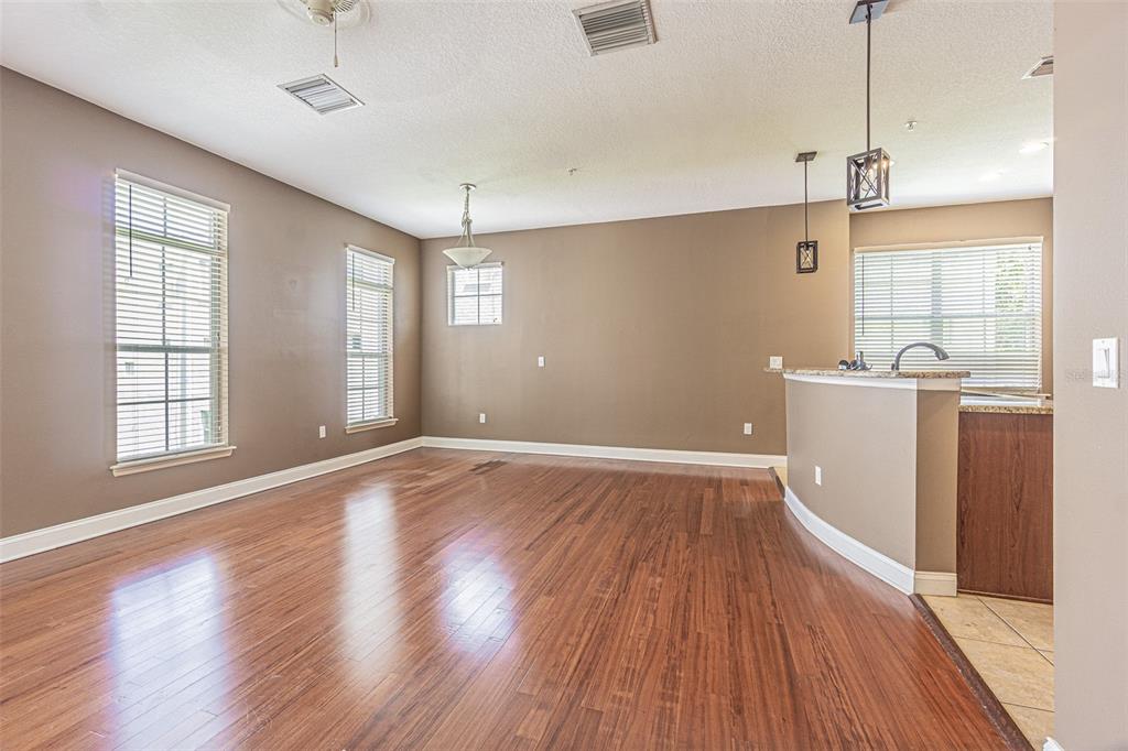 An open-concept living and dining area features brown walls, wood flooring, and a kitchen peninsula — 4511 LEGACY PARK DRIVE, TAMPA, FL