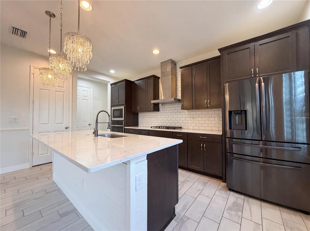 A kitchen features dark wood cabinets, a white quartz island, and stainless steel appliances — 12643 HORSESHOE BEND DRIVE, LITHIA, FL