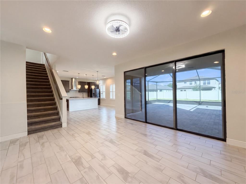 An open-concept living area with tile flooring, a carpeted staircase, and sliding glass patio doors — 12643 HORSESHOE BEND DRIVE, LITHIA, FL
