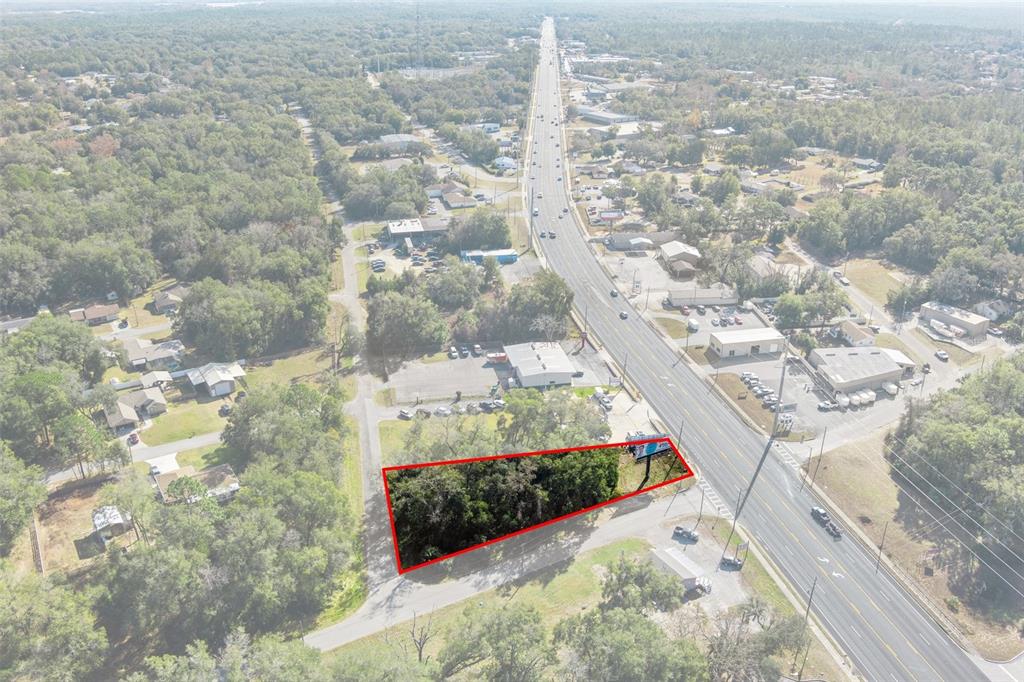 An aerial view shows a wooded, trapezoidal lot outlined in red next to a highway — 3413 & 3456 E GULF TO LAKE HIGHWAY, INVERNESS, FL