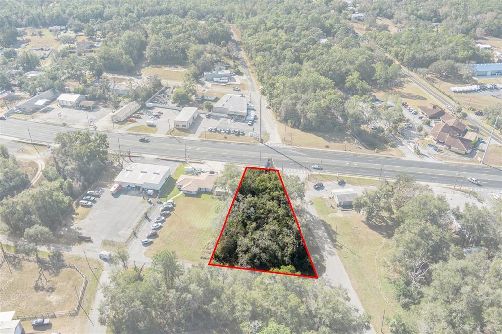 An aerial view shows a triangular, wooded lot outlined in red next to a highway — 3413 & 3456 E GULF TO LAKE HIGHWAY, INVERNESS, FL