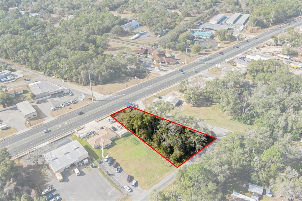 An aerial view shows a wooded, trapezoidal lot outlined in red next to a highway — 3413 & 3456 E GULF TO LAKE HIGHWAY, INVERNESS, FL