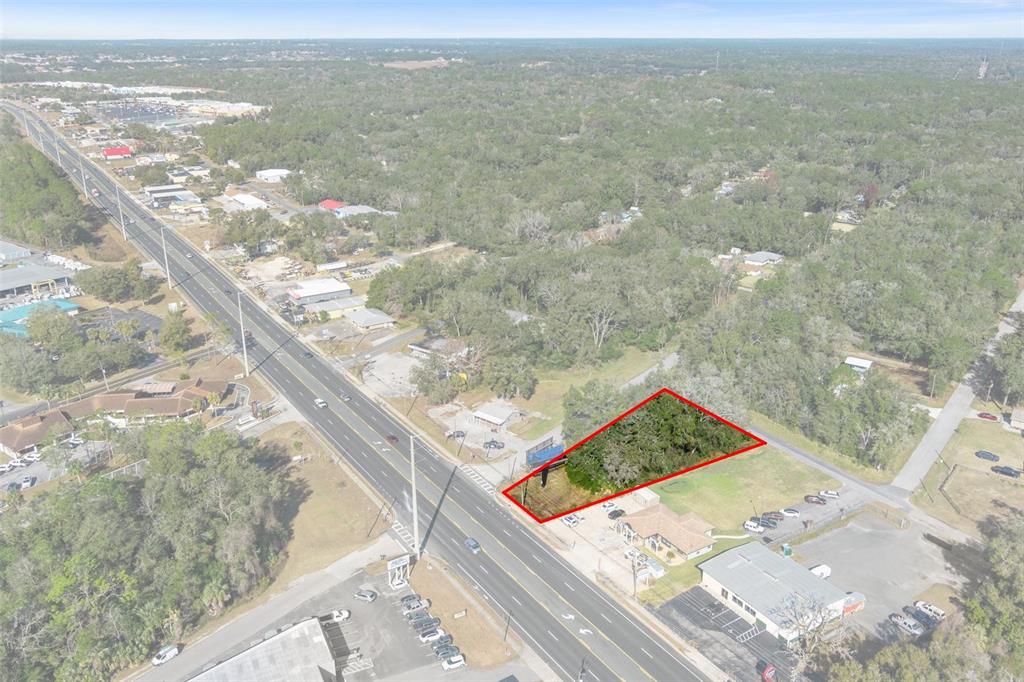 An aerial view shows a vacant, wooded lot outlined in red along a multi-lane highway — 3413 & 3456 E GULF TO LAKE HIGHWAY, INVERNESS, FL